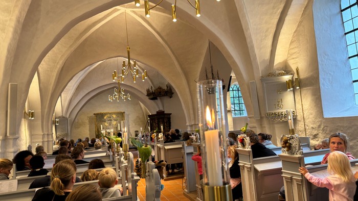 En stor kirkeindendomsrum med høje buer og mange lysstaker.