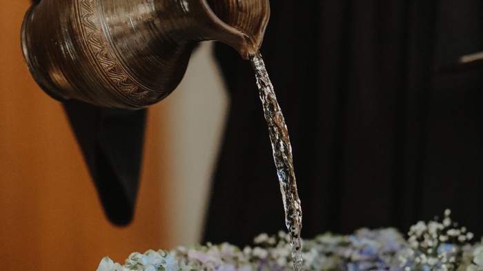Person gießt Wasser in eine Vase mit Blumen