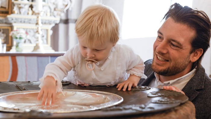 En mand og et barn spiser kage på en bord.