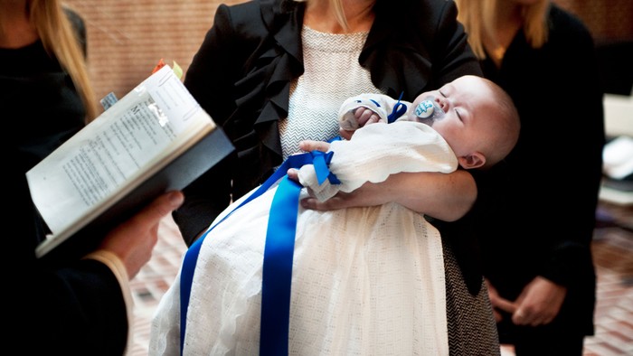 En kvinde i hvidt holdet et barn, der er omgivet af en blå bånd.