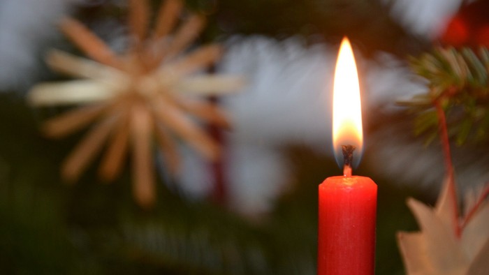 Brennende Kerze und Strohsterne am Weihnachtsbaum