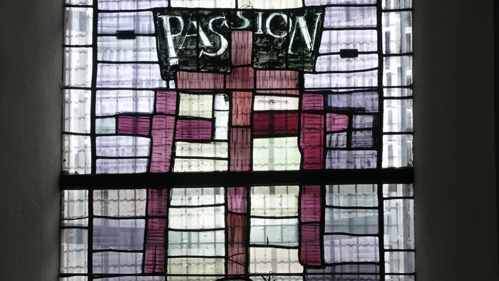 Buntglasfenster mit der Darstellung der „Passion“, einem Kreuz und religiöser Symbolik.