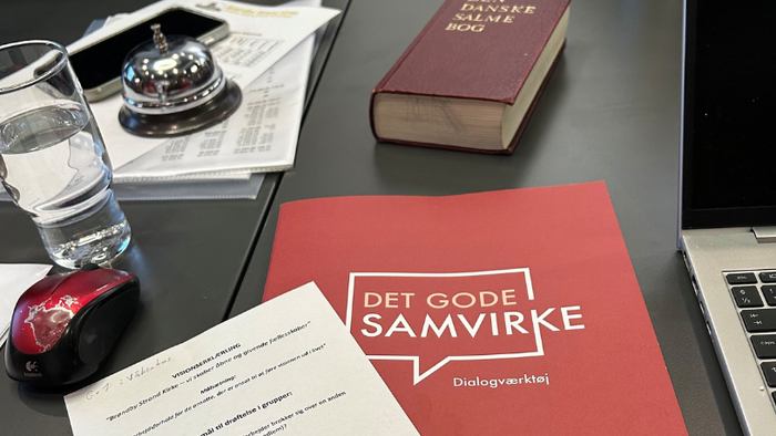 Bog, laptop, glas og papirer på bord med mønstre