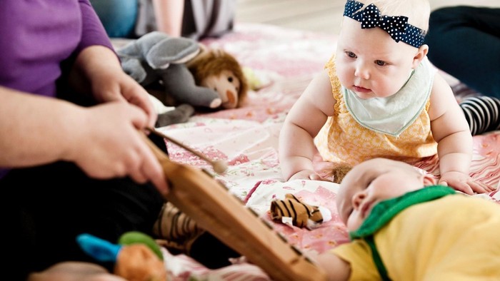 Et barn spiller med legetøj og en voksende.
