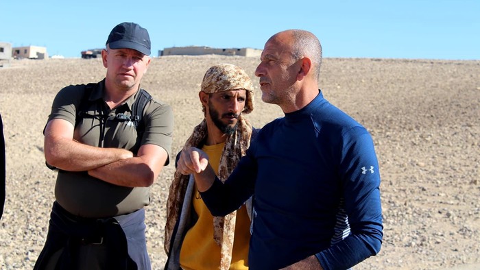 Tre mænd står i ørkenen og snakker.