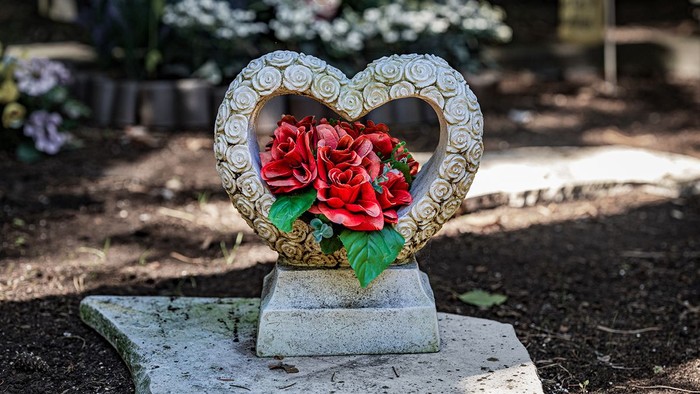 Ein herzförmiger Grabstein mit roten Blumen