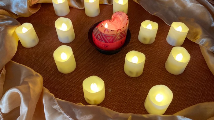 Mehrere angezündete Kerzen auf einem Tischtuch mit goldener Decke