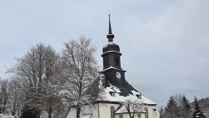 Weiße Kirche mit hohem Turm im Schnee.