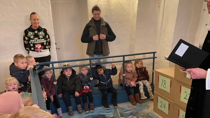 Børn samlede sig omkring en udstillingsmontre og betragtede en udstilling med interesse.