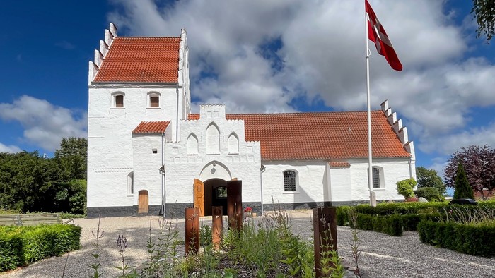 Hvid kirke med rødt tag og tyrkisk flag, der vajer.