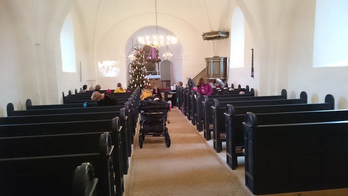 En kirke med folk, der sidder på bænkene og ser mod alteret