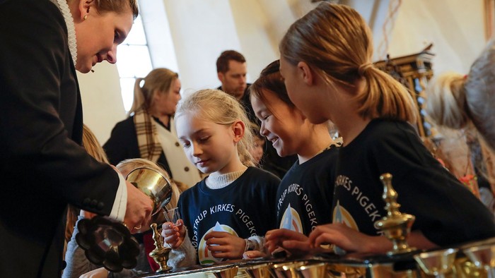 En gruppe børn og voksne ser på en udstilling af medaljer.