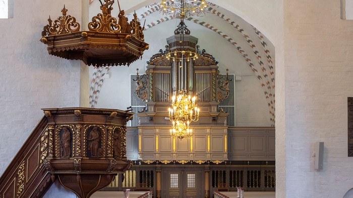 Indre del af kirke med orgel og lysende kælderkrone