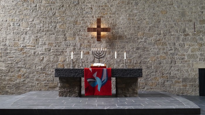Ein Altar mit Kreuz und Menora vor einer Steinwand