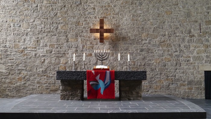Ein Altar mit Kreuz und Menora vor einer Steinwand