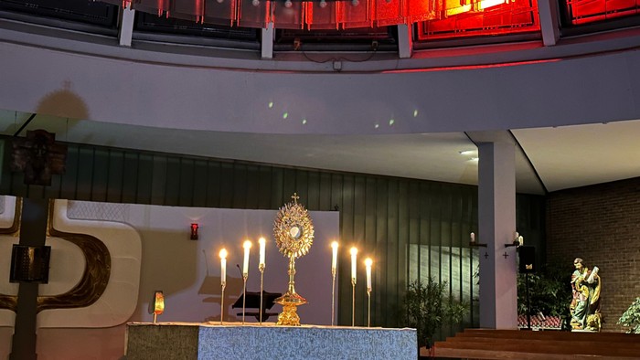 Innenraum einer Kirche mit Altarraum, Kerzen und Blumen