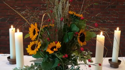 Tisch mit Kerzen, Blumen und Gesangbüchern