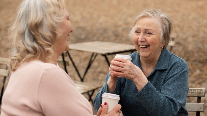Zwei ältere Frauen sitzen an einem Tisch und trinken Kaffee.