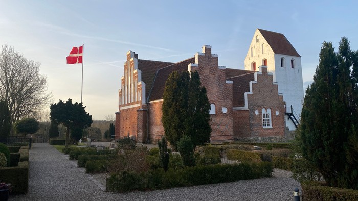 En rød murstenskirke med dansk flag på en klar dag