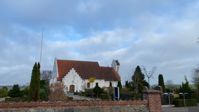 En hvid og rød stald med tagtegn og mursten i forgrunden