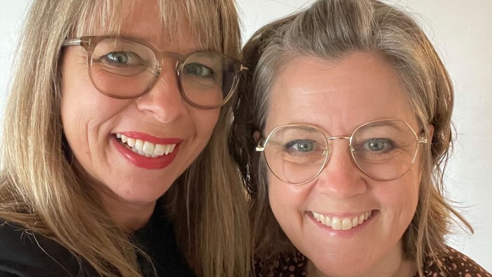 To kvinder med briller smiler til kameraet