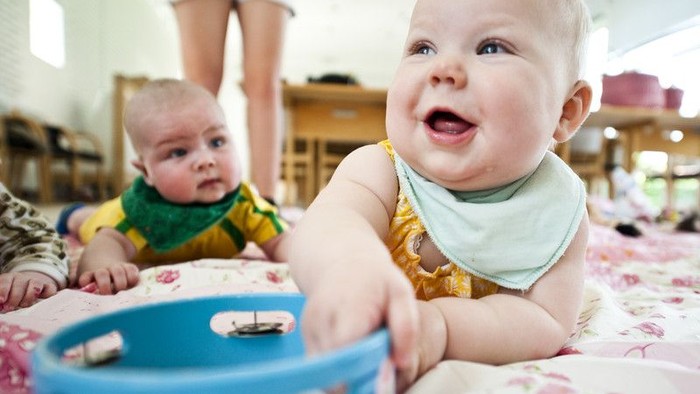 To børn spiller på gulvmatte med legetøj.