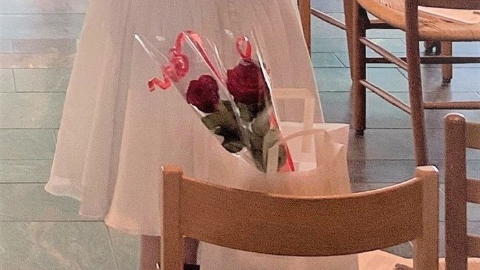 En kvinde står med ryggen til kameraet med en blomsterafsnit i håret.