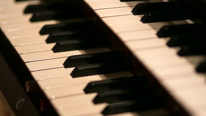 Nahaufnahme der Tasten eines Flügelklaviers mit weichem, warmem Licht, das ihre Textur und den Kontrast hervorhebt.