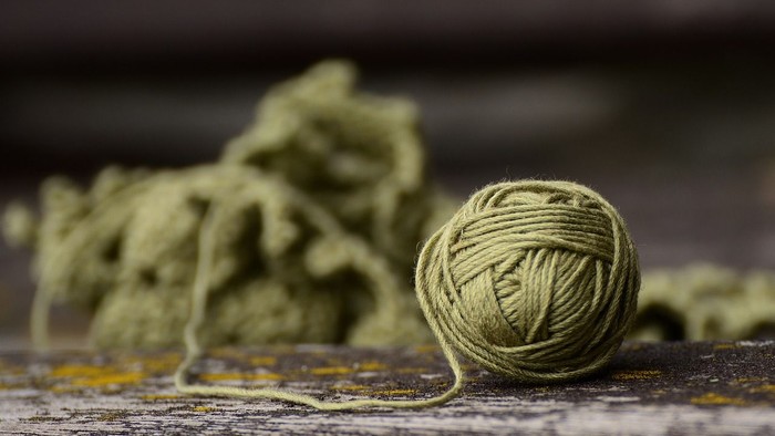 En kugle grøn garn og et udfalet garnstykke på en mørk flade