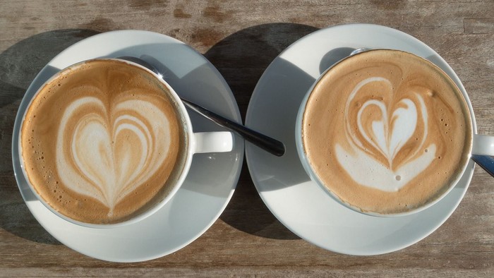Zwei Tassen Kaffee mit Herz-Art auf Holztisch