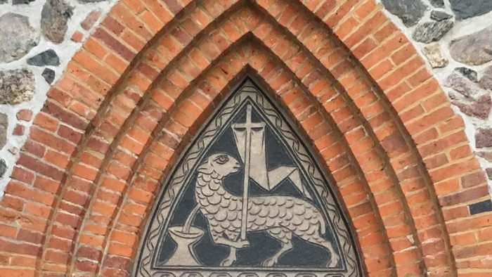 Eingangstür der Dorfkirche Alt-Wittenau, über der Tür ein Opferlamm
