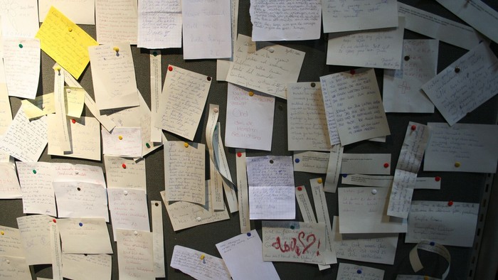 Völlig mit beschriebenen Zetteln bedeckte Pinnwand.