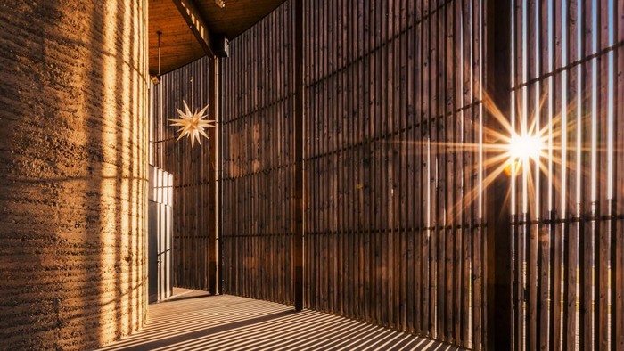 Holzvertäfelung in einem Raum mit zwei Lichtquellen, die durch die Schlitze scheinen.