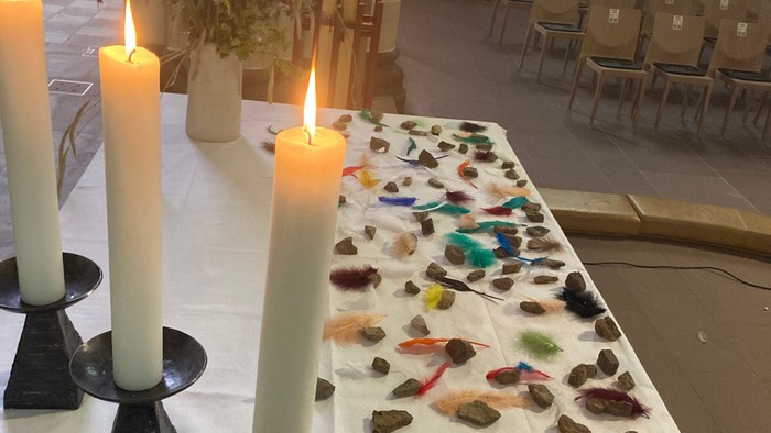 Kerzen, Steine und Federn auf einem Tisch in einer Kirche