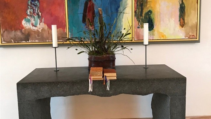 En moderne indretning med sort bord, to lysekøn, og farvede malerier på væggen