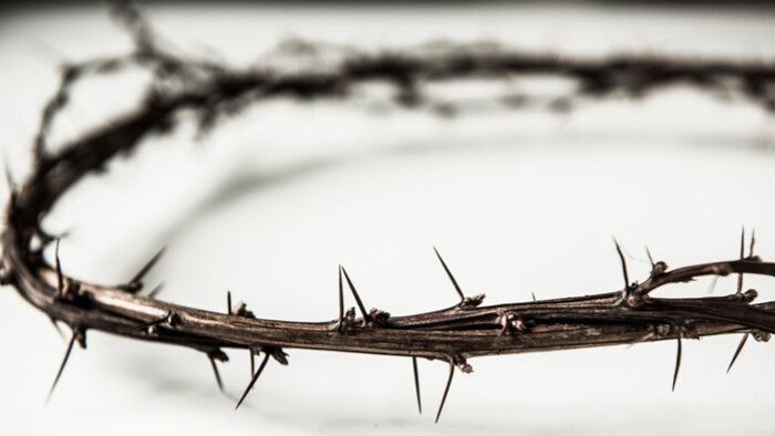 Et nærbillede af en tornet lidelseskrans, indviklet flettet af skarpe torne.