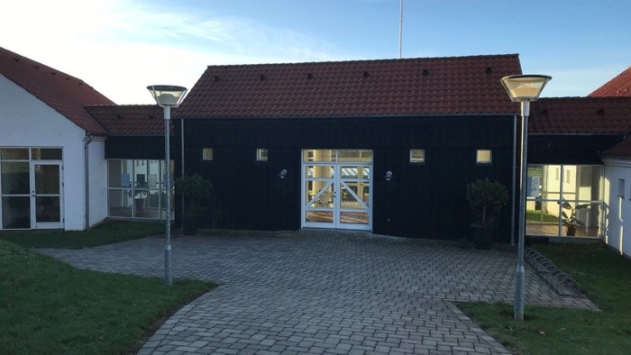 En sort building med røde tag og to lysekøler på en købberstensvej