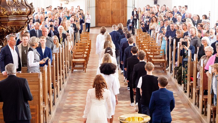 En bryllupsceremoni finder sted i en kirke med mange gæster.