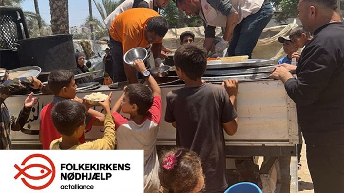 Børn og voksne serverer mad i en træflokke under palmetræer