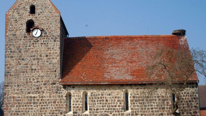 Alte Kirche mit Turm und Zifferblatt unter blauem Himmel