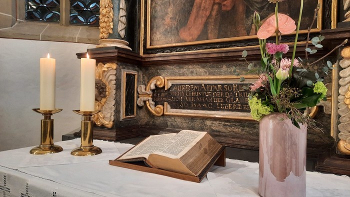 Ein Altar mit Kerzen, Buch und Blumen in einer Kirche