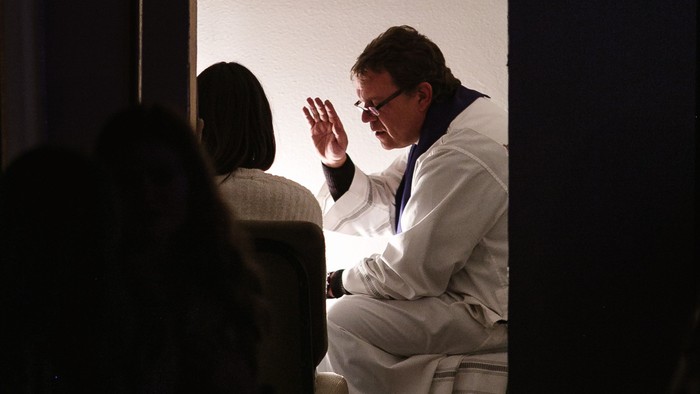 Ein Mann in weißem Anzug winkt auf einer Bühne.