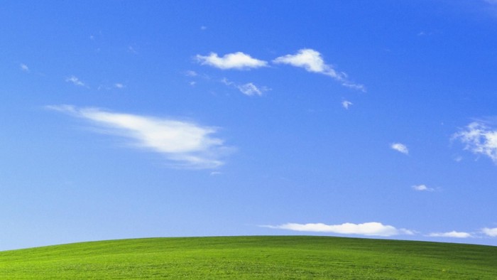 Rolling green hills under blue sky with white clouds