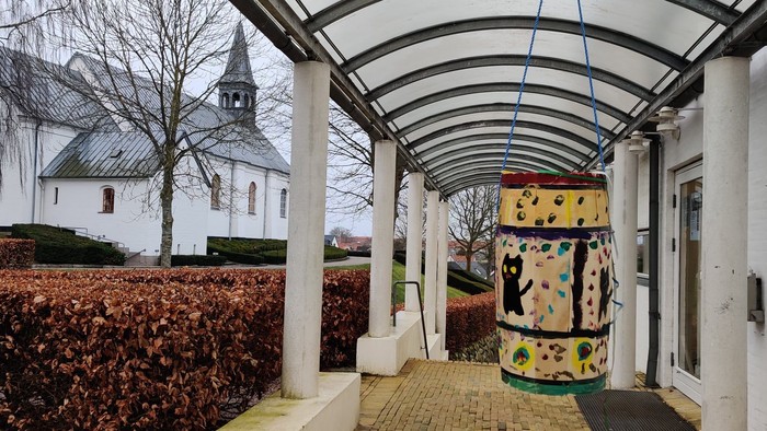 Fastelavnstønde dekoreret med katte hængende under halvtag ved hvid kirke