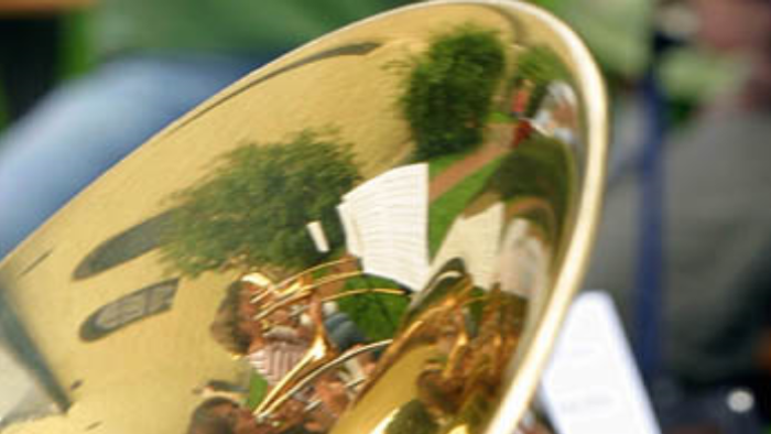 Ein goldfarbener Gegenstand spiegelt Bäume und Menschen wider