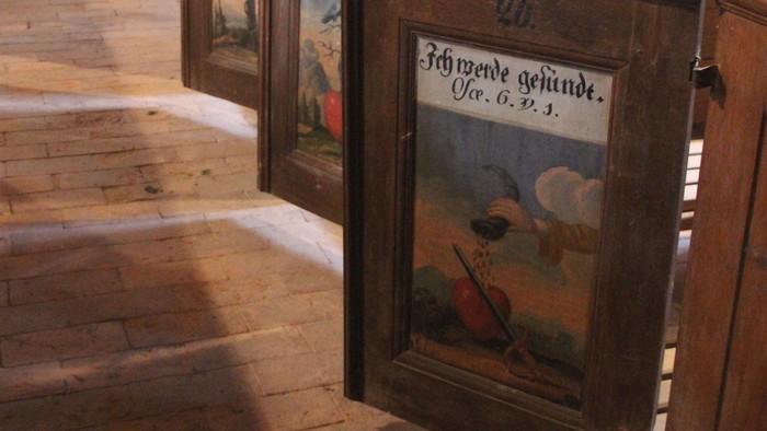 Holzbänke mit Bildern in Kirchenraum