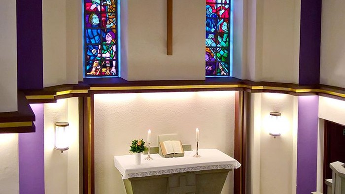 Die Kirche mit einem Altar und zwei buntem Fenstern