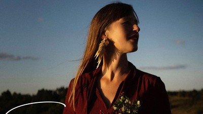 En eftertænksom kvinde holder blomster i skumringen og fremkalder temaer om naturens styrke og ro.