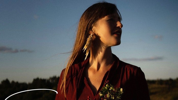 En eftertænksom kvinde holder blomster i skumringen og fremkalder temaer om naturens styrke og ro.