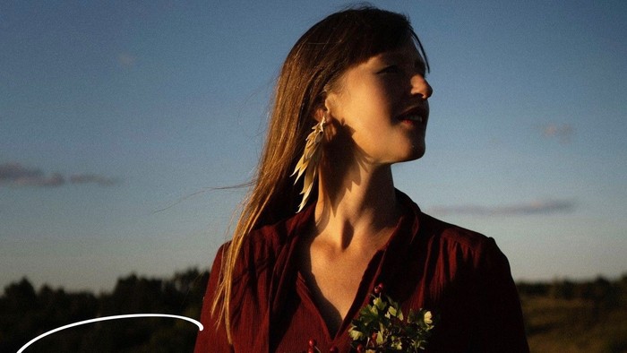 En eftertænksom kvinde holder blomster i skumringen og fremkalder temaer om naturens styrke og ro.